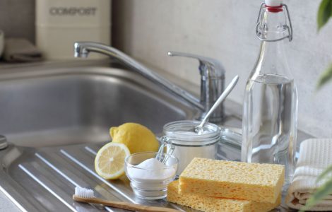 Vinaigre, citron, éponge, brosse à dents et serviettes sur l'évier de cuisine