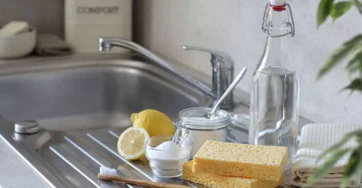 Vinaigre, citron, éponge, brosse à dents et serviettes sur l'évier de cuisine