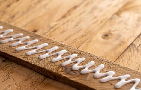 De la colle blanche répandue sur un élément en bois prêt à être assemblé