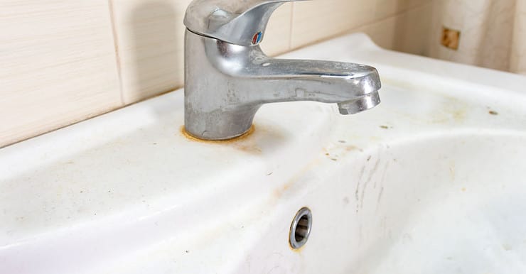 Un vieux lavabo sale avec des taches de rouille et de calcaire