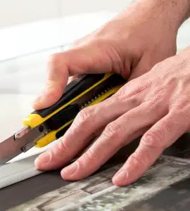 Un homme en train de couper une toile avec un cutter