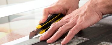 Un homme en train de couper une toile avec un cutter