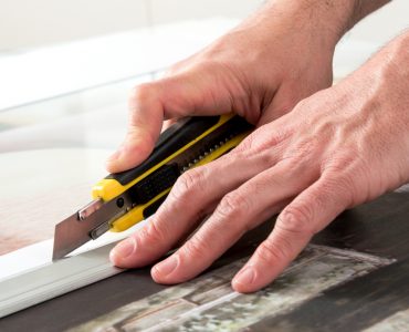 Un homme en train de couper une toile avec un cutter