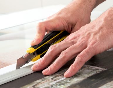 Un homme en train de couper une toile avec un cutter