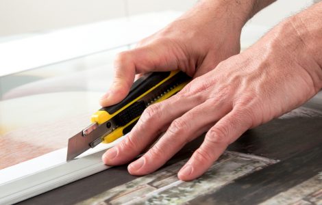Un homme en train de couper une toile avec un cutter
