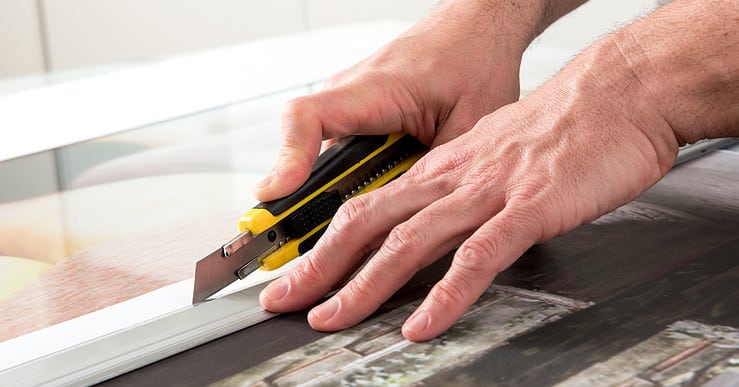 Un homme en train de couper une toile avec un cutter