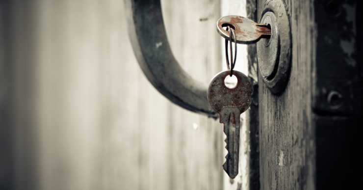 Une clef rouillée insérée dans la serrure d'une vieille porte en bois