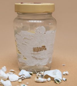 Des étiquettes retirées restent collées sur un pot de verre
