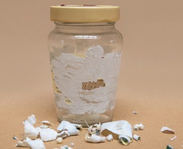 Des étiquettes retirées restent collées sur un pot de verre