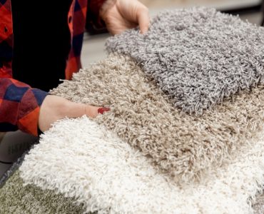 Une femme choisit un tapis gris parmi les modèles du magasin