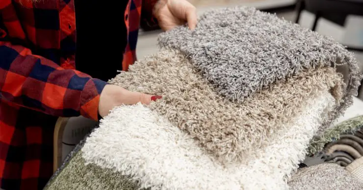 Une femme choisit un tapis gris parmi les modèles du magasin