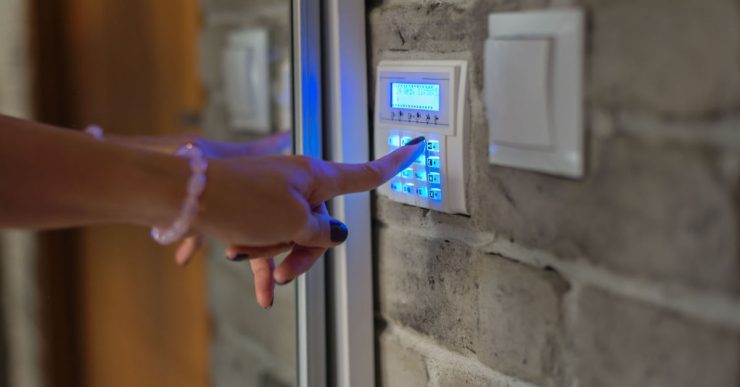 Une femme entre un mot de passe sur le clavier de l'alarme maison