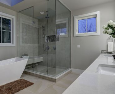 Une salle de bains grise avec grande douche à l'italienne en verre