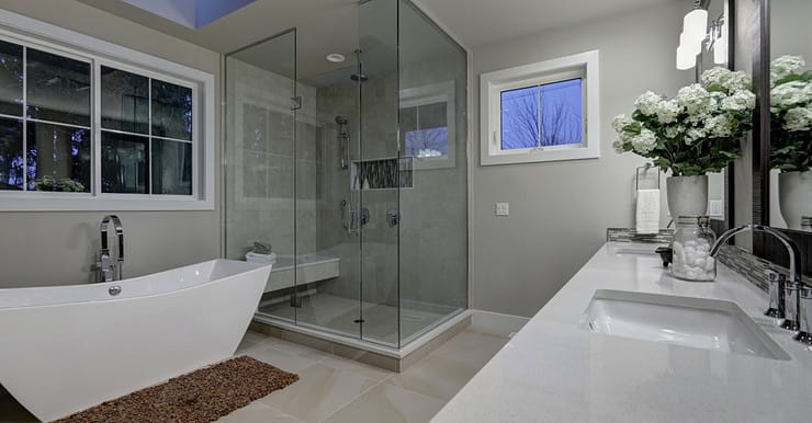 Une salle de bains grise avec grande douche à l'italienne en verre