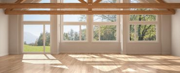 Une pièce vide avec parquet et armatures de toit en bois, fenêtre panoramique