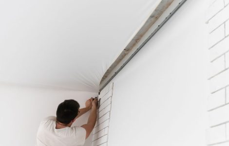 Un ouvrier en train d'étendre le plafond suspendu d'une pièce