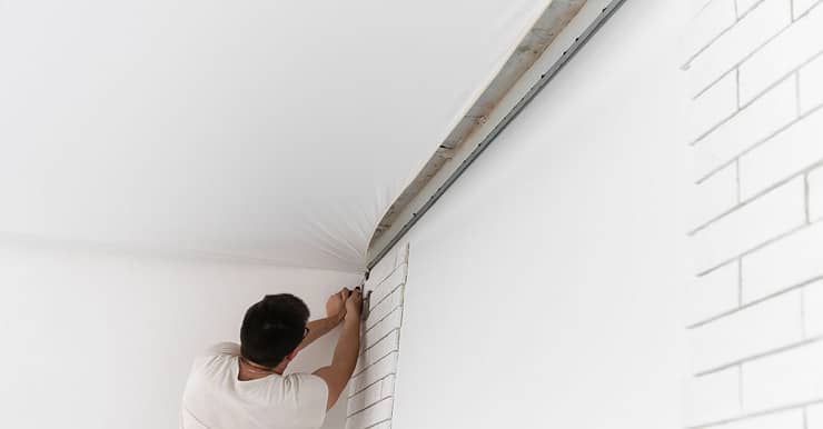 Un ouvrier en train d'étendre le plafond suspendu d'une pièce