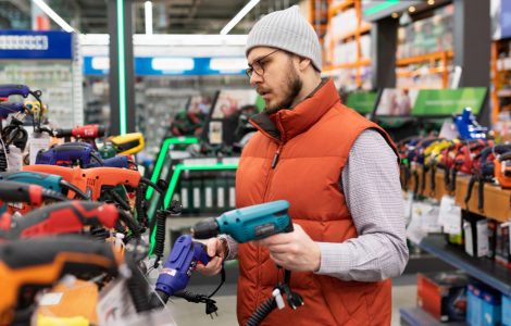 Un homme en train de choisir une perceuse dans un magasin