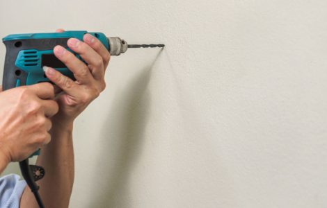 Zoom sur les mains d’un homme utilisant une perceuse pour faire un trou dans un mur