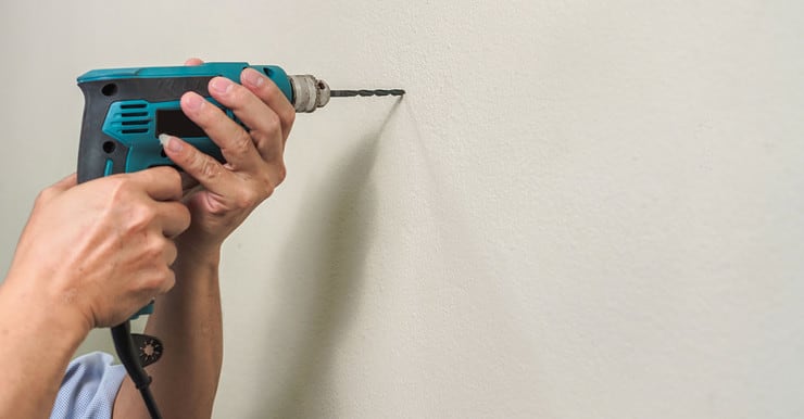 Zoom sur les mains d’un homme utilisant une perceuse pour faire un trou dans un mur