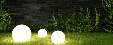 Trois lampes boules allumées posées sur le gazon la nuit