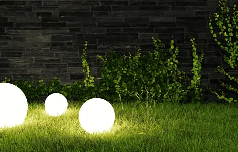 Trois lampes boules allumées posées sur le gazon la nuit