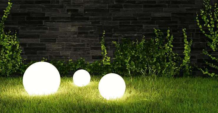 Trois lampes boules allumées posées sur le gazon la nuit