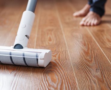 Une personne nettoie le parquet avec un aspirateur sans fil
