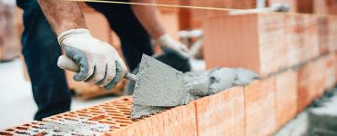 Un maçon en train de construire un mur en briques monomur