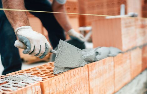 Un maçon en train de construire un mur en briques monomur