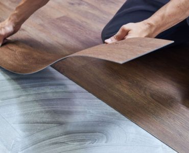 Un homme en jean en train de poser un revêtement de sol en vinyle