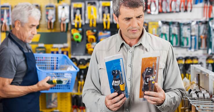 Un homme choisit entre deux fers à souder dans un magasin