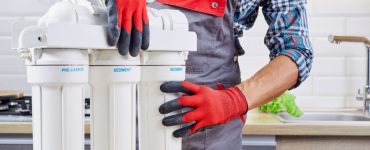 Un homme en gants rouges et gris en train de vérifier le filtre à eau