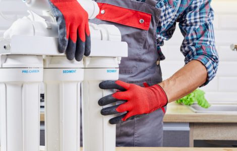Un homme en gants rouges et gris en train de vérifier le filtre à eau