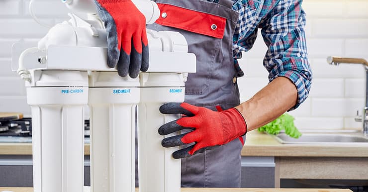 Un homme en gants rouges et gris en train de vérifier le filtre à eau