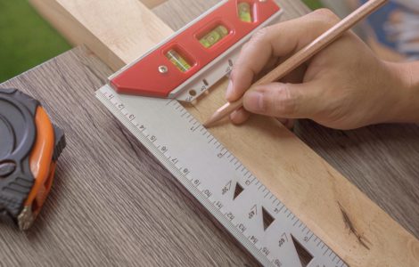 Zoom sur les mains d'un homme traçant une ligne droite à l'aide d'une équerre à niveau