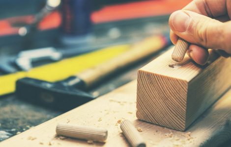 Un homme insère une mèche en bois dans un élément de menuiserie pour l'assemblage