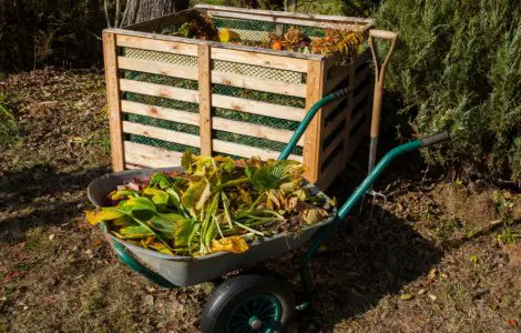 Un bac à compost et une brouette remplie de déchets organiques dans le jardin