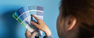 Une femme tient une palette de couleurs bleus contre un mur