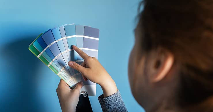 Une femme tient une palette de couleurs bleus contre un mur