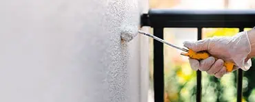 Focus sur la main d’une personne en gant blanc peignant le mur d’une terrasse avec un rouleau