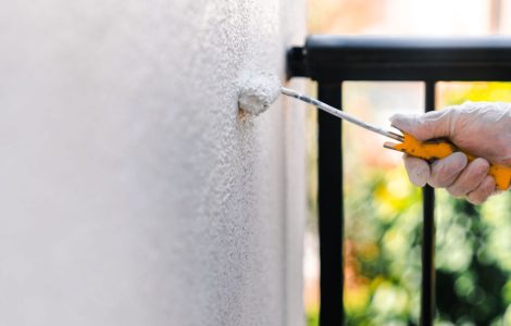 Focus sur la main d’une personne en gant blanc peignant le mur d’une terrasse avec un rouleau