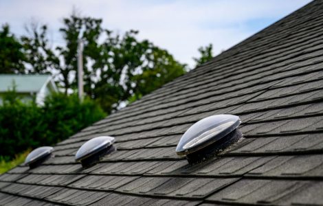 Focus sur 3 puits de lumière sur le toit en ardoise noir d’une maison
