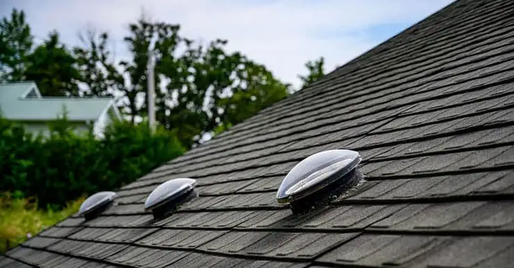 Focus sur 3 puits de lumière sur le toit en ardoise noir d’une maison