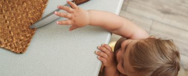 Un enfant essaie d'attraper un couteau posé sur le plan de travail de la cuisine