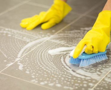Femme nettoyant le sol carrelé avec une brosse
