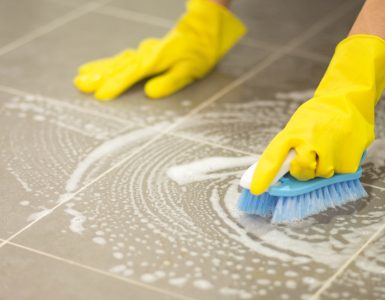 Femme nettoyant le sol carrelé avec une brosse