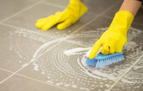Femme nettoyant le sol carrelé avec une brosse