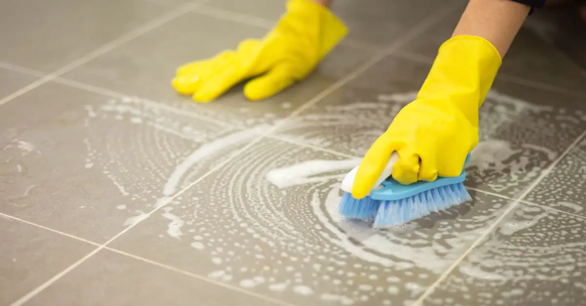 Femme nettoyant le sol carrelé avec une brosse
