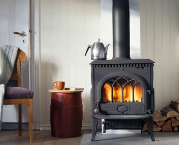 Une chambre avec un poêle de chauffage en bois et une chaise avec plaid